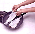 fish being placed in a frying pan