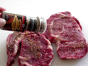 An image of meat being seasoning